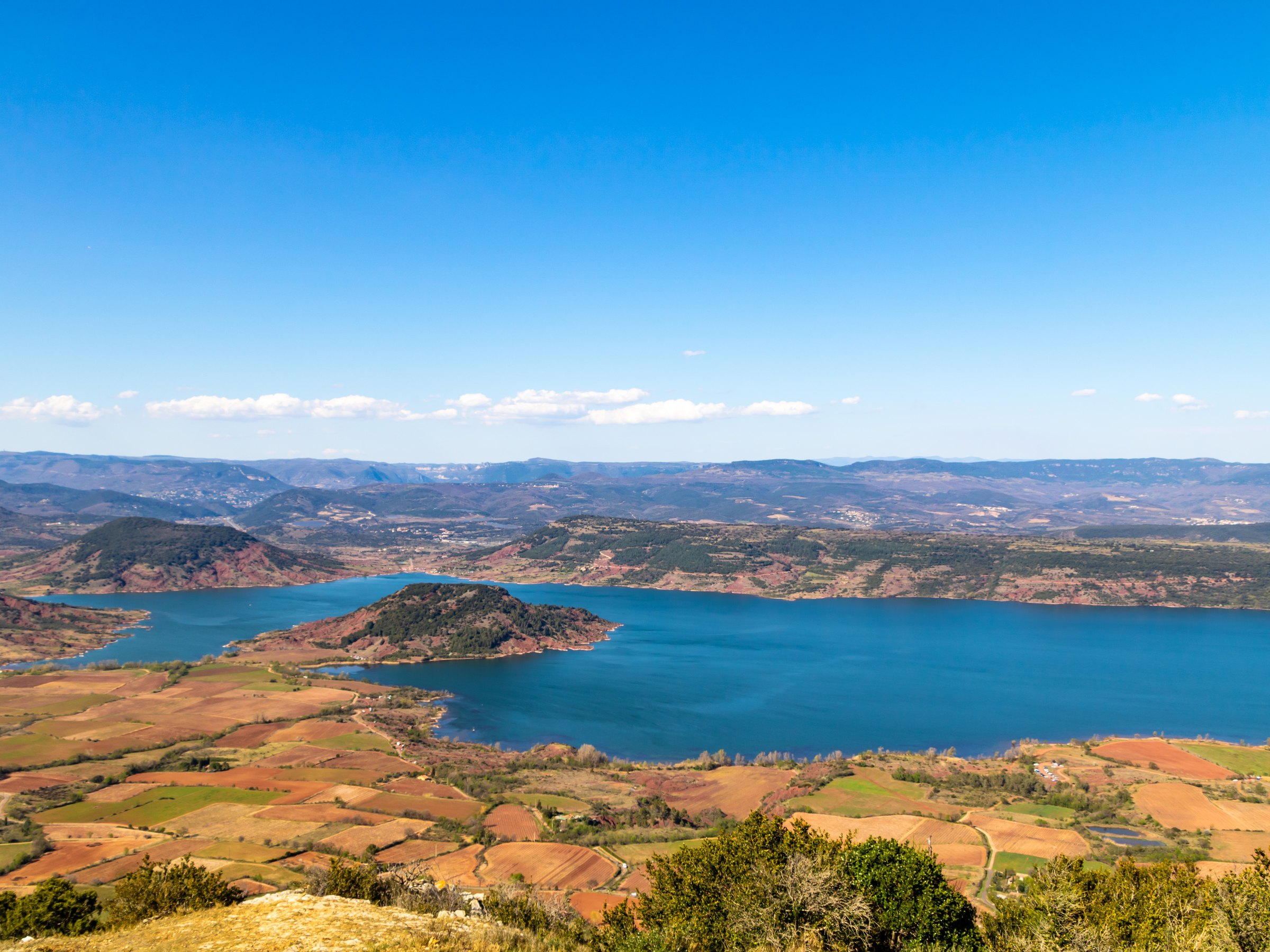 Le lac du Salagou vu d’en haut, ses rives de terre rouge et les collines jusqu’à l’horizon