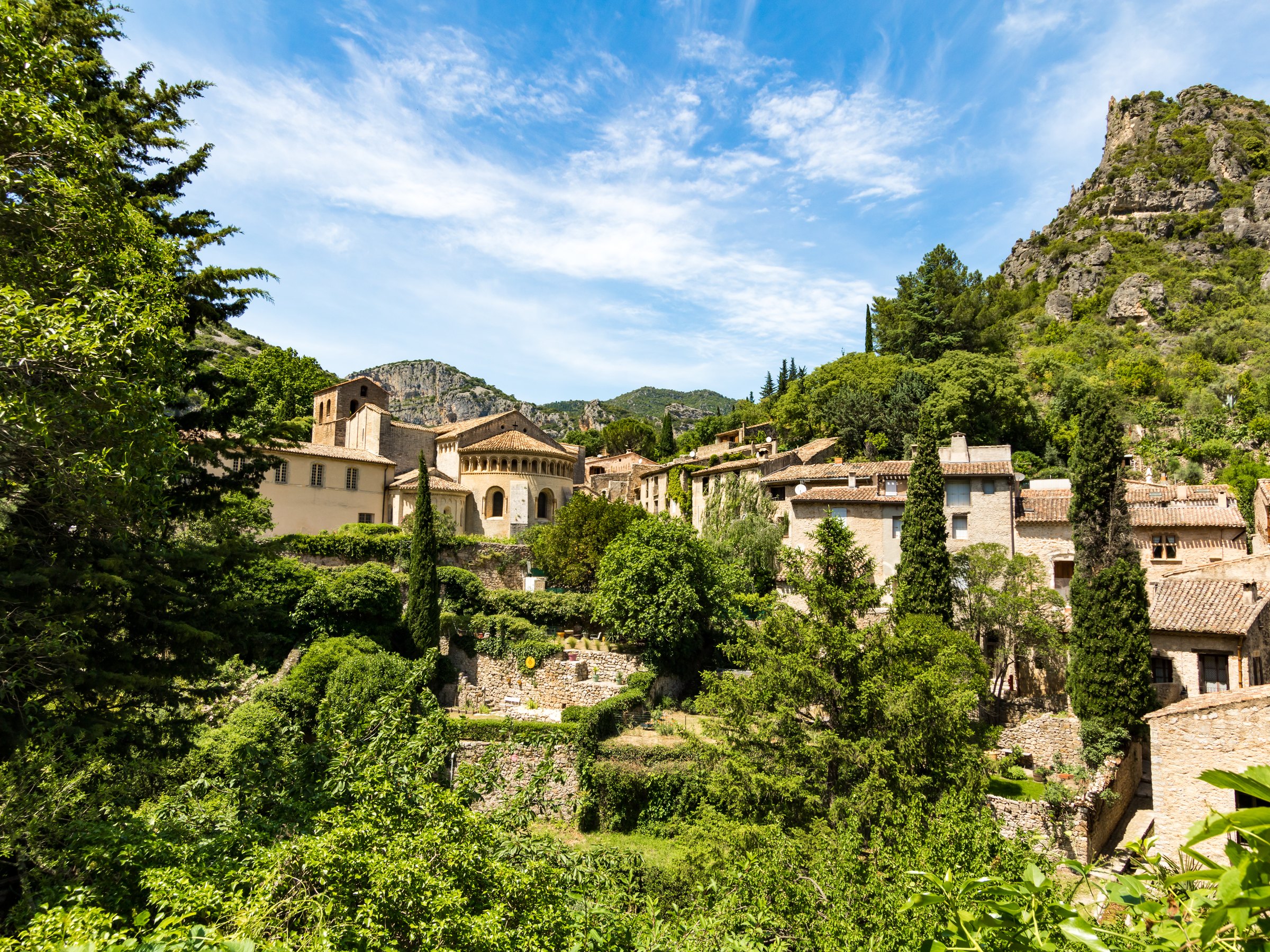 Le village de Saint-Guilhem-le-Désert dans la verdure, au pied des falaises