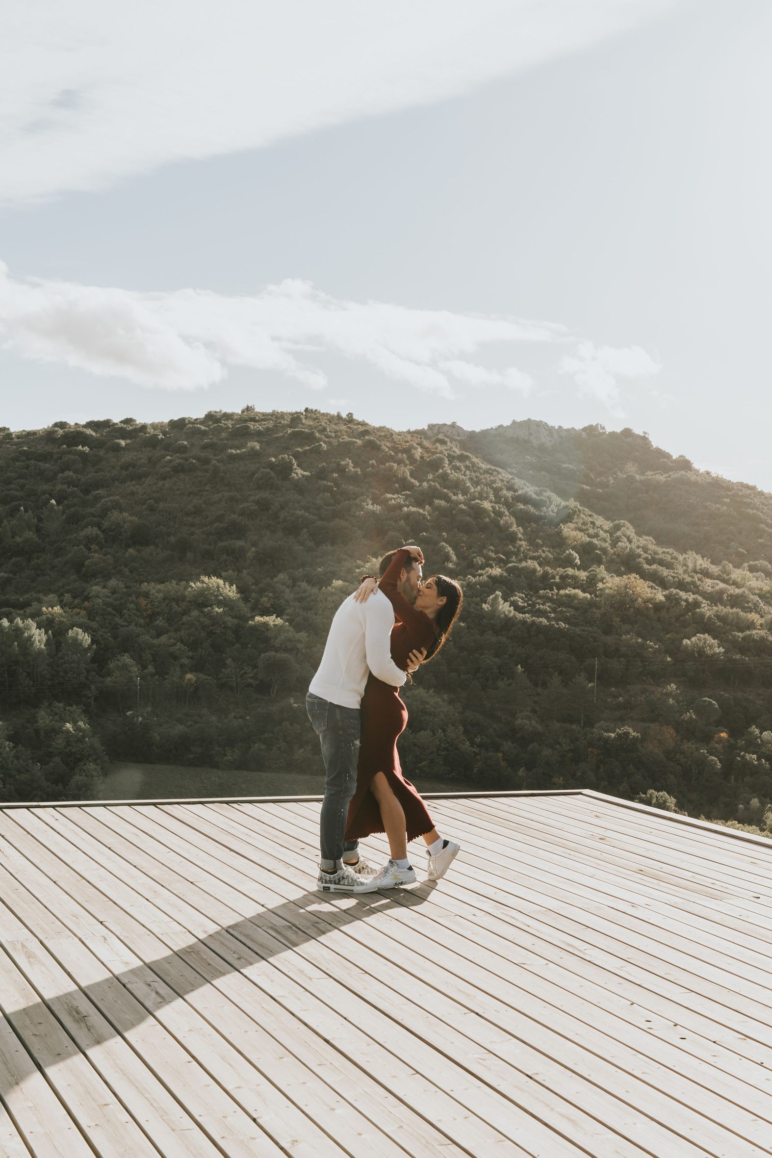 Couple enlacé sur la terrasse d’un lodge à contre-jour, les collines de la garrigue derrière, Souki Lodges & Spa