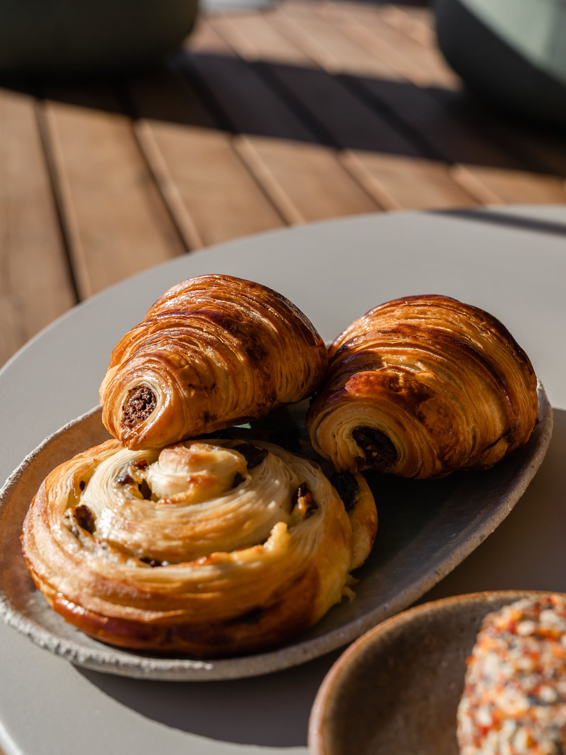 De près : pains au chocolat et brioche aux raisins sur une assiette, en pleine lumière