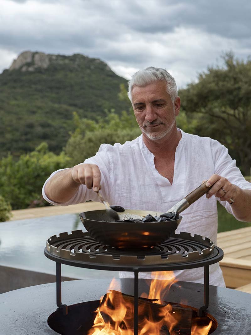 Gilles au brasero : il retourne des moules dans une poêle posée sur les flammes, le Pic au fond