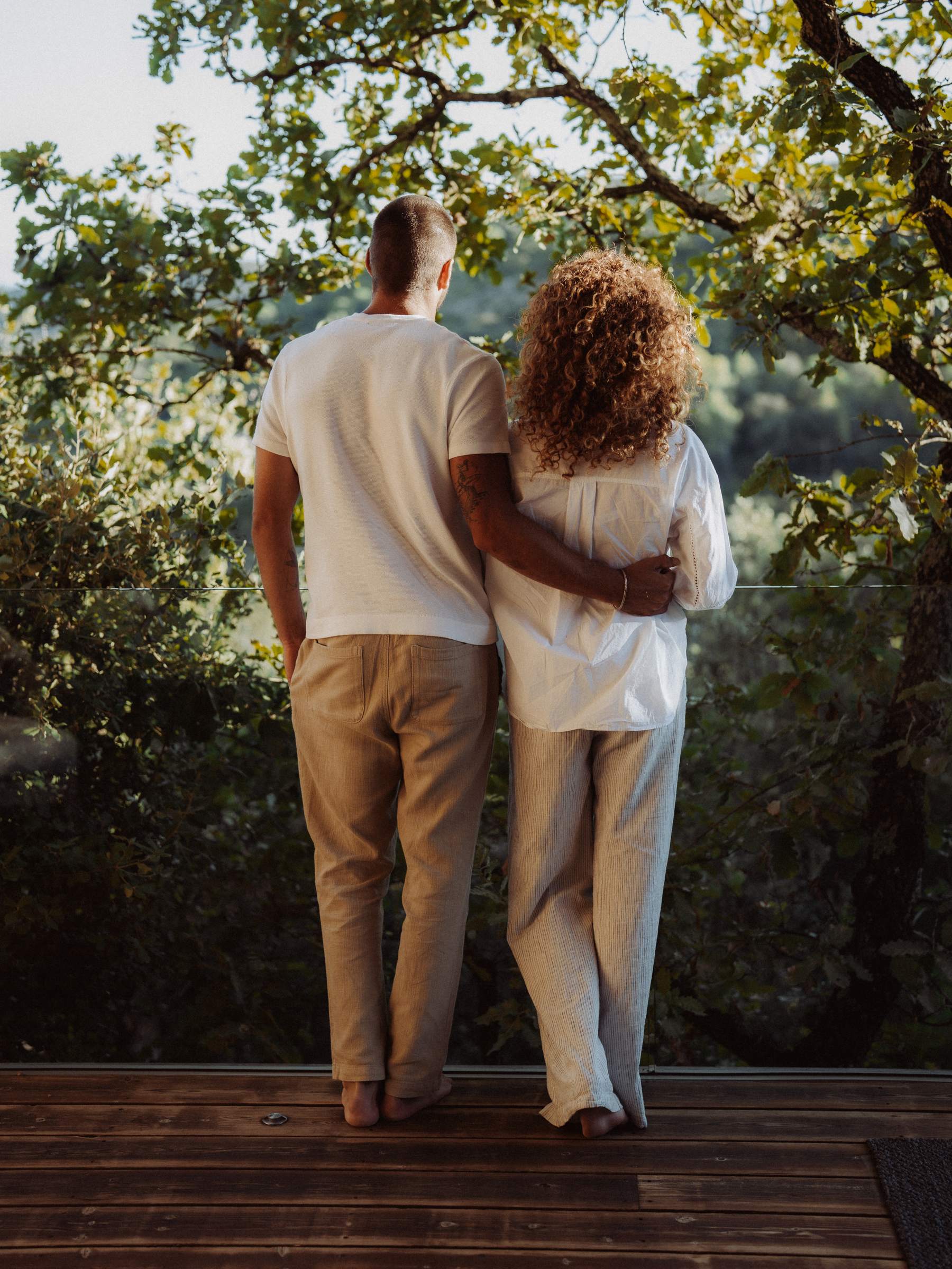Un couple de dos sur la terrasse au soleil couchant, face aux collines